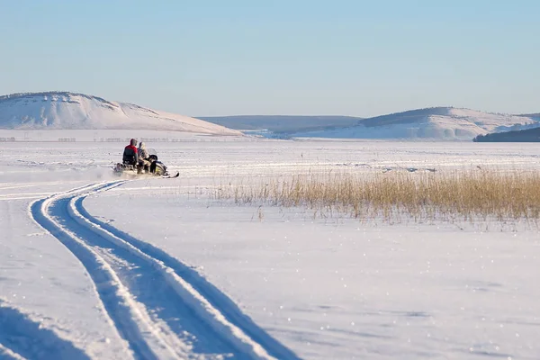 山の背景に冬の湖に沿って漁師とスノーモービルに乗っています Parnaya クラスノヤルスク地域 ロシア — ストック写真