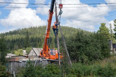 Belogorsk, Kemerovo bölgesi, Rf-13 Ağustos 2016: aleti ahşap iletim kutup yapısı ve düzeltme kendisine bir yüklemenin daraltılmasını vinç patlamaya ile zincir ile tırmandı.