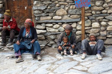 Kagbeni, Mustang / Nepal - 21 Ağustos 2014: Meçhul Nepal halkı, Mustang Krallığı 'nın Kagbeni köyündeki taş duvarın yanındaki kaldırımda oturuyor.