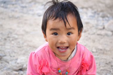 Lo Mantang, Yukarı Mustang / Nepal - 24 Ağustos 2014: Pembe elbiseli, Tibet kökenli gülümseyen küçük bir kızın portresi