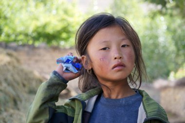 Tsarang, Yukarı Mustang / Nepal - 23 Ağustos 2014: Tibet uyruklu, yüzünde güneş yanığı olan üzgün küçük bir kızın portresi.