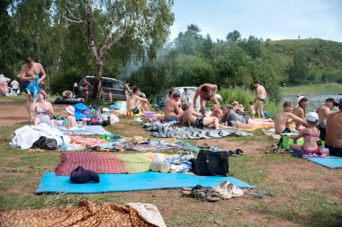 Round Lake, Krasnoyarsk Bölgesi / Rf - 3 Ağustos 2019: Bir yaz günü, insanların şirketleri gölün ormanlık kıyısındaki yatak örtülerinde dinlenirler.