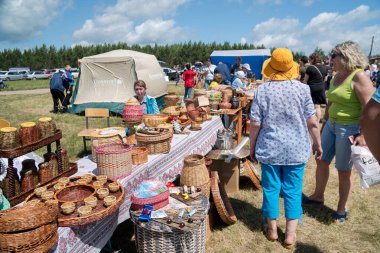 Parnaia, Sharypovskiy bölgesi, Krasnoyarsk bölgesi / RF - 5 Temmuz 2019: Alıcılar, Karatag Müzik ve El Sanatları Festivali 'nde hasır ve sahte ürünlerle bir tezgahın önünde duruyorlar. 