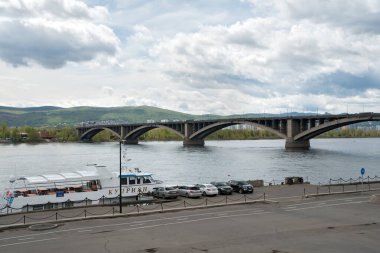 Krasnoyarsk, Krasnoyarsk Bölgesi / RF - 22 Mayıs 2019: Bir turizm gemisi, sol kıyıdaki Communal Köprüsü (1961) yakınlarında park halindeki araçlarla rıhtımda duruyor. 