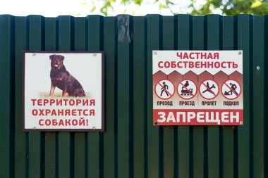 Parnaya, Krasnoyarsk Bölgesi / RF - 9 Ağustos 2018: Özel bir sitenin metal çitlerinde tehdit ve yazıtları yasaklayan işaretler - giriş yasak, bölge bir köpek tarafından korunuyor -.