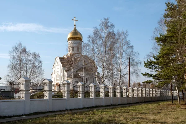 Orthodox church of St. Andrew the First-Called (2011) with a fence in the foreground on a sunny autumn day in the city of Lesosibirsk. Krasnoyarsk region. Russia.
