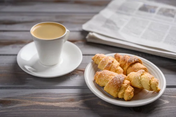 Caffè e biscotti fatti in casa bagel su sfondo di legno. Vicino a un giornale — Foto Stock