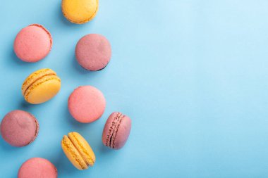 Renkli Fransız ya da İtalyan makaron yığını mavi masa üzerinde arkaplan için kopyalama alanı