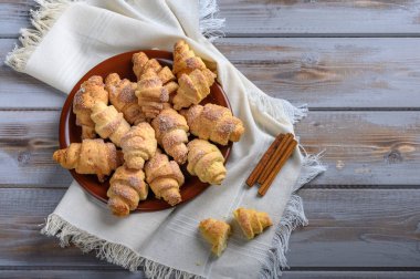 Ahşap bir arka planda keten peçetenin üzerinde simitlerden ev yapımı kurabiye hamuru. Tarçın çubuklarının yanında.