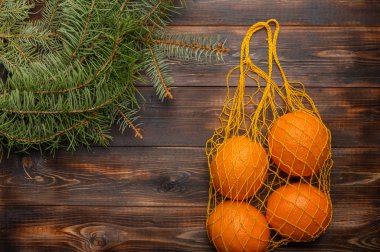 Ahşap arka planda ızgara şeklinde portakallar. Köknar dallarının yanında. Noel konseri