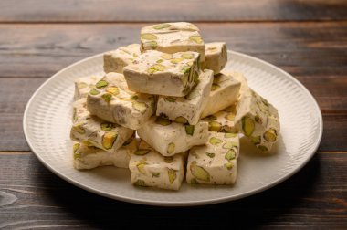 Açık arkaplanda seramik tabakta fıstıklı Doğu Arap fındığı tatlısı. Kapat.