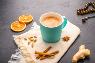 Geleneksel Hint masala çayı. Sütlü ve baharatlı. Koyu taştan arka planda peçeteli.