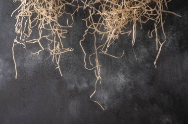 Saman gövdeleri tebeşir lekeli koyu bir arkaplanda yukarıdan sarkıyor. 