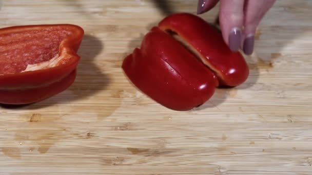 Femme coupant du poivre avec un couteau sur la planche à découper dans une cuisine — Video