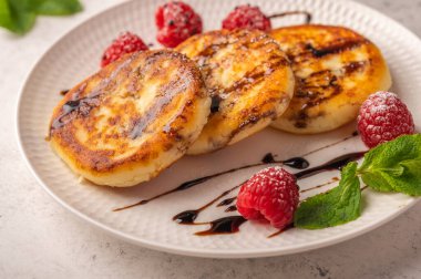 Ev yapımı ahududu, şurup ve nane şekerli peynirli kekler açık ahşap arka planda seramik bir tabakta. Kapatın. Metin için alanı kopyala