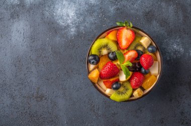 Koyu arkaplanda farklı malzemelerle taze meyve salatası. Sağlıklı beslenme. Uzayı metin için kopyala. Üst görünüm