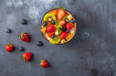Koyu arkaplanda farklı malzemelerle taze meyve salatası. Sağlıklı beslenme. Uzayı metin için kopyala. Üst görünüm