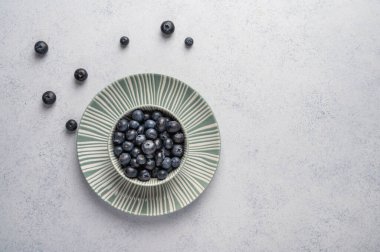 Yaban mersini, açık ahşap arka planda bir tabakta kaseye konur. Üst Manzara. Metin için alanı kopyala