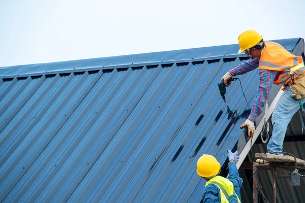 Construction worker wearing safety harness using secondary safety device connecting into 15 mm static rope using as fall restraint shingle on top of the new roof.