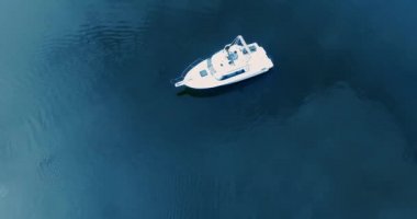 Sıcak yaz gününde motorlu tekneyle güzel mavi göl manzarası. Güzel genç kadın güvertedeki yatta dinleniyor, yürüyor ve öpüşüyor.