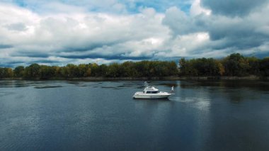 Sıcak yaz gününde motorlu tekneyle güzel mavi göl manzarası. Güzel genç kadın güvertedeki yatta dinleniyor, yürüyor ve öpüşüyor.
