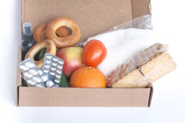 Coronavirus yemek teslimatı. Çeşitli yiyeceklerle birlikte bağış kutusu. İçinde yağ, konserve yiyecek, mısır gevreği ve makarna olan karton bir kutu açın. Boşluğu kopyala.