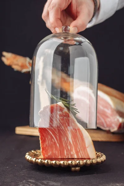 Şef bir cam et ve biberiye örtüsü açar. Geleneksel İspanyol jamonu arka plandaki cam kubbenin altında. Jamon serrano, italyan parma, hamon iberico, prosciutto, leg hamon