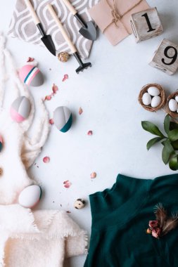 Mutlu Paskalyalar. Beyaz bir masada bıldırcın yumurtası, renkli yumurta ve bahçe malzemeleri. Bahar konsepti.