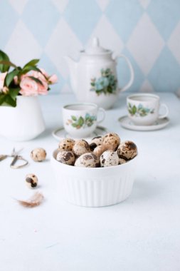 Paskalya bahar dekoratif kompozisyonu ev yapımı bıldırcın yumurtası ve güllerle. Beyaz ve mavi arka planda. Tatil kutlaması süslemeleri. Mutlu Paskalyalar. Kutlama paskalya arkaplanı.