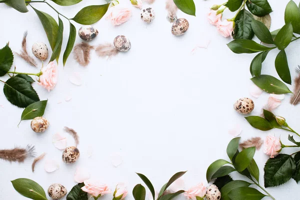 Easter concept. Easter of circle frame for your banner with feathers, branches and buds rose and quail eggs on white background with place for text. Top view. Flat lay. Postcard for Spring Holidays