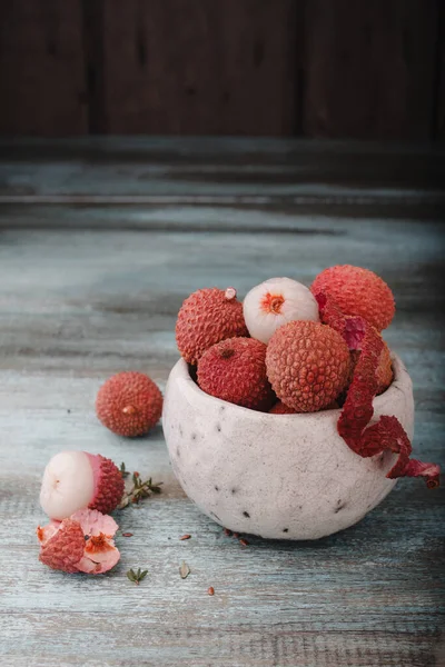 Kopyalama alanı olan Litchi chinensis. Eski ahşap arka planda bir kasede taze litchi meyveleri. Çiğ kırmızı organik liçi meyvesi yemeye hazır..