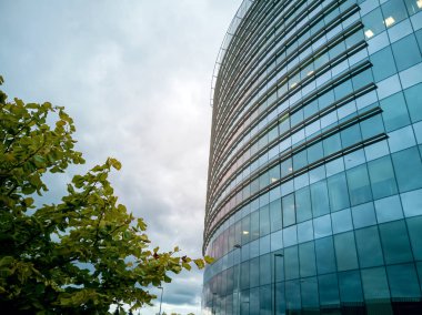 Gökdelenlerin modern cam siluetleri. İş binası. Gri gökyüzünde gökdelen manzarası. Pencereli yüksek bir evin parçası. 