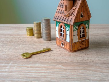 Bir ev modeli, bir yığın para ve ahşap masa üzerinde altın anahtar..