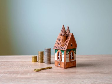 Bir ev modeli, bir yığın para ve ahşap masa üzerinde altın anahtar..