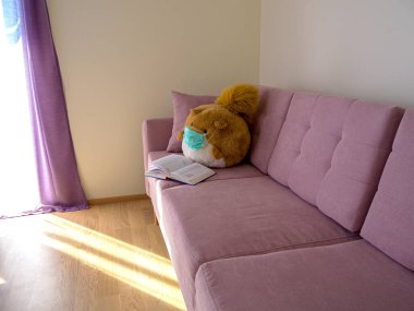 Sincap, koruyucu maske takıp kitap okuyan koca bir sincap oyuncağı doldurdu. Koronavirüs koruması. Dünyada virüs salgını. 