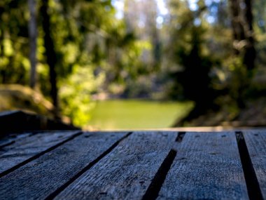 Seçici odaklanma. Arkasında yeşil göl olan boş ahşap iskele. 