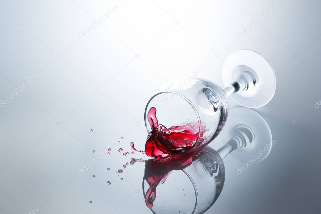 Red wine spilled out of a falling glass with reflection on the surface
