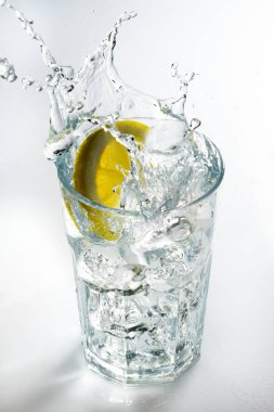 Bir bardak beyaz bir arka plan üzerinde sıçramasına limon