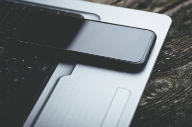 Siyah smartphone ile ahşap arka plan üstünde laptop.