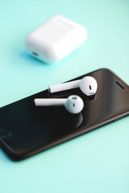Mavi arka planda izole edilmiş akıllı telefon ve kablosuz kulaklıklar.. 