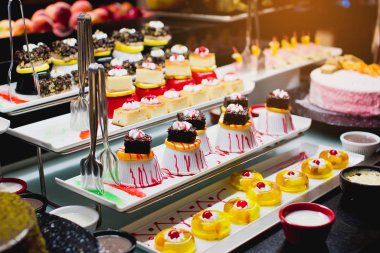 Delicious reception candy bar dessert table. Pieces of sweets cake dessert on a plate.