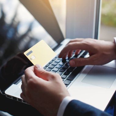 Erkekler kredi kartı tutarken ve dizüstü bilgisayar kullanırken. İnternetten alışveriş.
