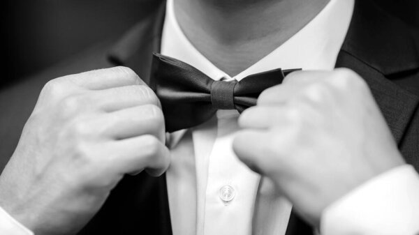 Close up of a man adjusting tie.