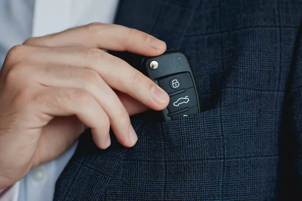 Man in suit puts car keys in breast pocket.