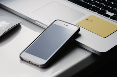 Masada siyah ekranlı bir bilgisayar ve telefon var.
