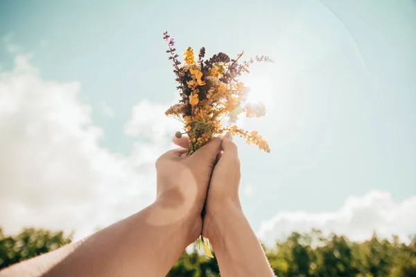 Par de manos sosteniendo un ramo de flores — Foto de Stock