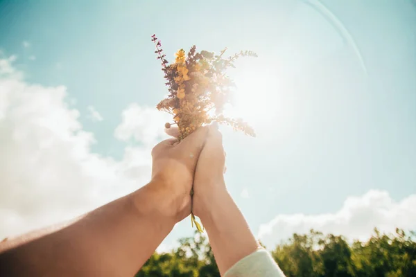 Par de manos sosteniendo un ramo de flores — Foto de Stock