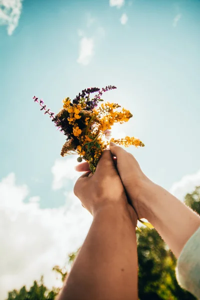 Bir buket çiçek tutan iki el.