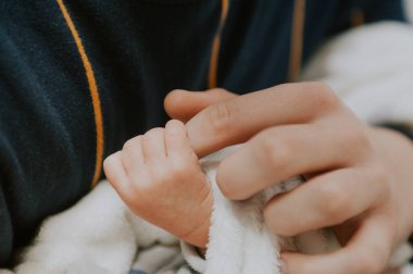 Yeni doğmuş bebek babasının parmağını tutuyor. 