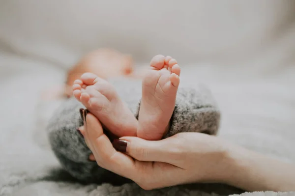 Anne, bebeğin ayaklarını elinde tutuyor.